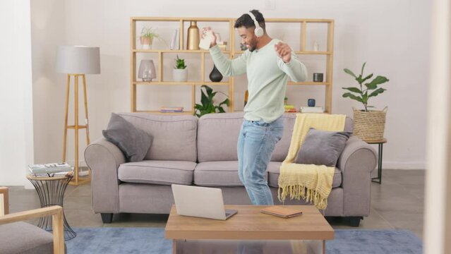 Man, dancing and listening to music in living room with headphones for fun, streaming or entertainment at home. Happy male with headset enjoying dance to audio track or sound in lounge on smartphone