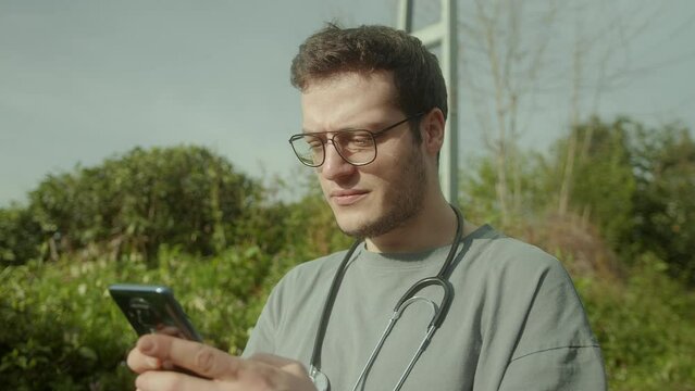 Handsome doctor with glasses, using a health app on his smartphone to provide innovative and personalized healthcare services