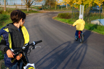 Fototapeta na wymiar Teenager watches how his brother ride bicycle. Healthy lifestyle,environmentally transport concept