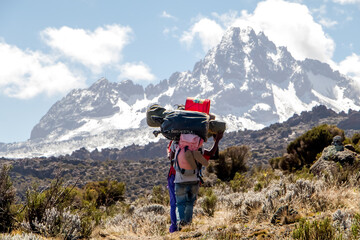 Mount Kilimanjaro with native porters carrying pack on their heads