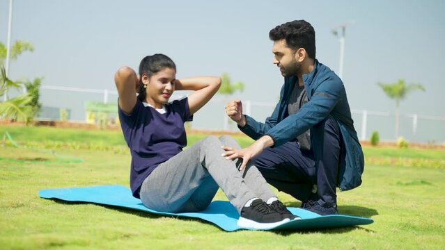 Fitness trainer encouraging or cheering up woman for exercising by pushing up limits - concept of motivation, guidance and athletic