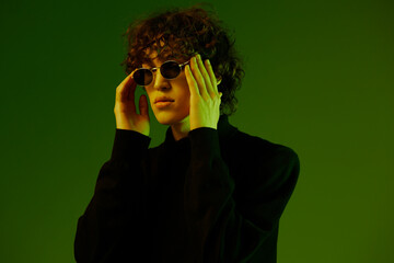 Man wearing glasses fashion and style model, hipster teen lifestyle, portrait green background mixed neon light, copy space