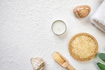 Spa treatment concept. Natural spa cosmetics products, sea salt, sea stone, massage brush, towel on white textured background from above. Spa background with a space for a text, flat lay, top view
