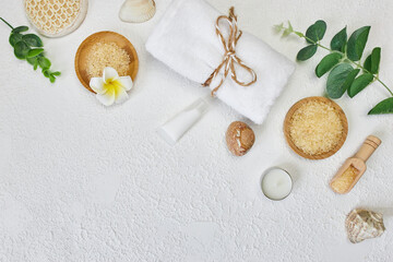 Spa treatment concept. Natural spa cosmetics products, sea salt, sea stone, massage brush, towel on white textured background from above. Spa background with a space for a text, flat lay, top view