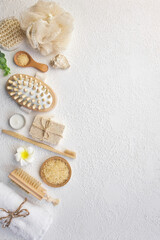 Fototapeta na wymiar Spa treatment concept. Natural spa products, sea salt, sea stone, massage brush, towel on white textured background from above. Spa background with a space for a text, flat lay, top view, vertical