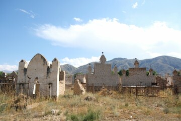 Tian Shan, Kyrgyzstan - circa August 2022: A traditional muslim cemetery at the foot of mountains...