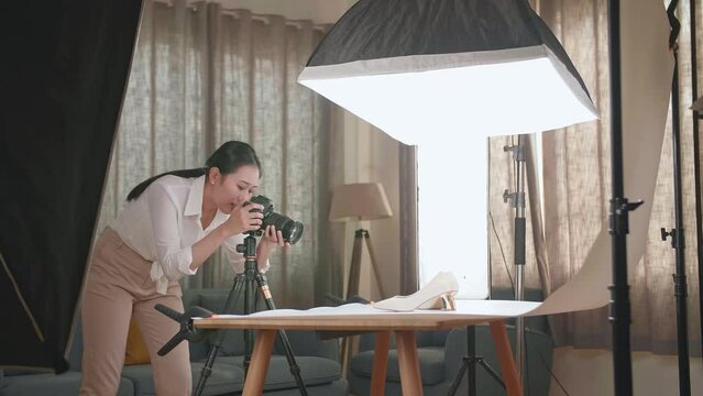 Asian Female Photographer Checking The Photos Of Women'S Shoes After Taking Them In Home Studio 
