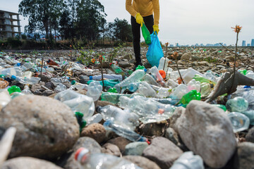 Male volonteer collecting plastic bottles garbage on the beach in trash bag. Earth day,...