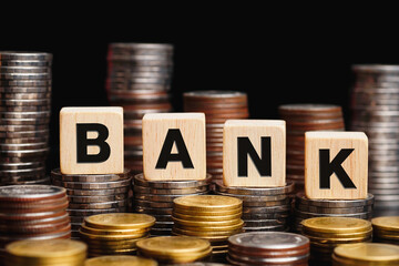 Wooden cubes with the word BANK on a money pile of coins. Finance and banking networking. investment or taking loan.