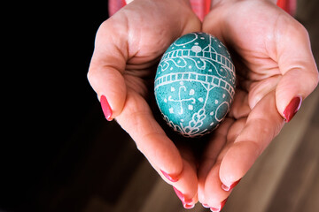 The girl holds an Easter egg in her palms. Place for text. Easter theme. Close-up