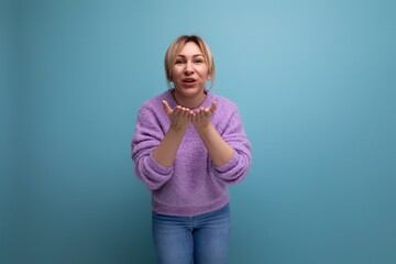 Fototapeta premium attractive blond young millennial woman in casual look sends a kiss on a bright background with copy space