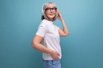 middle age business. mature lady with gray hair listens to music in wireless headphones on studio...