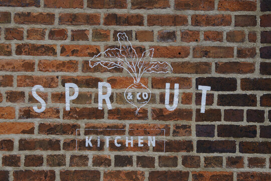 Logo of Sprout & Co Kitchen painted with white paint on red brick wall in Dublin Ireland 