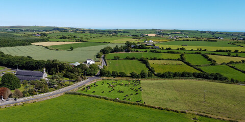 Old church and cemetery, green farm fields, top view. Picturesque fields in the south of Ireland, landscape. Sacred Heart Roman Catholic Church. Green grass field under blue sky