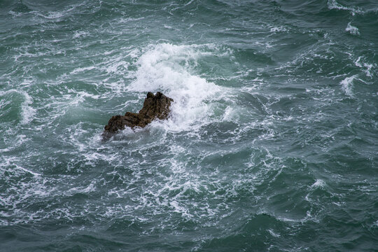 big dark stone in the Atlantic Ocean washed over by crashing waves on the Irish coast