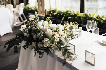 Table for guests, served with cutlery, flowers and crockery and covered with a tablecloth.
