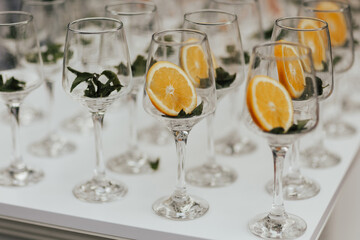 wine glasses on a white table with slice of oranges are preparing to create an aperol spritz.