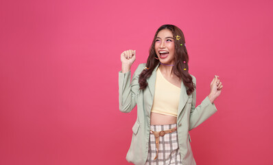 Portrait cheerful positive asian woman with raised hands and fists open mouth Girl get happy, enjoy life isolated on pink copy space background.