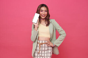 Happy smiling Asian teen woman showing smartphone mockup of blank screen on pink studio background.