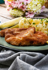 Pork chop served with mashed potatoes and pickled cucumber.