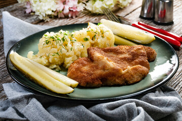 Pork chop served with mashed potatoes and pickled cucumber.