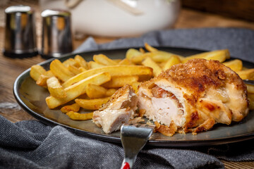 Fried chicken breast stuffed with bacon and cheese served with chips and salad.