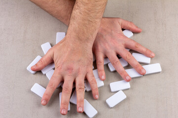 man's hands shuffle inverted white dice of domino board game on gray background top view close-up