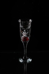 A glass of water and a cherry falling into the water