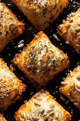 Puff pastry stuffed with spinach sprinkled with mix of seeds, close up view. Delicious snack on the party.