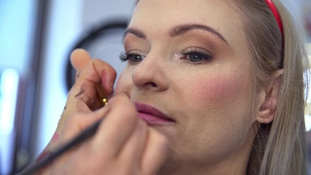 Makeup artist applies lip makeup using pink lipstick