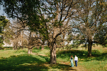Family walk together on a sunny summer day. Loving couple in the park. Woman and man relax in nature. Back view.