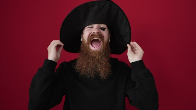 Young redhead man wearing wizard costume smiling confident over isolated red background