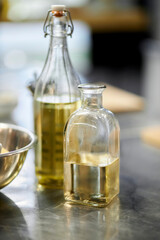 olive oil in glass bottles stands on the work surface in the restaurant kitchen. Two olive oil glass transparent bottle with cork stand on table on kitchen space room.