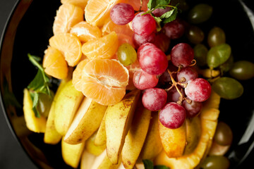 fruit slices on a plate, close-up. Fruit slices are beautifully laid out on plate close-up. Assortment of sliced fruits on plate