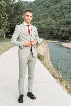 Young teenage boy buttoning his gray suit. Ready for a prom night.