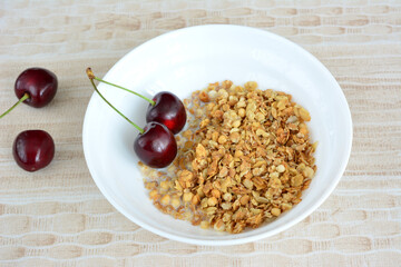 A bowl of granola with cherries on top isolated on beige background