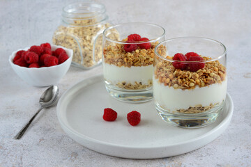 healthy dessert with yoghurt, granola and fresh raspberry in drinking glass  