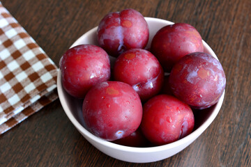 A bowl of plums on a table isolated, close-up