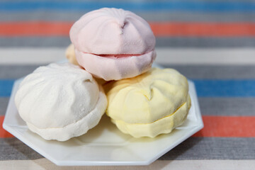Delicious fresh multi-coloured marshmallows lie in a saucer, on a served table
