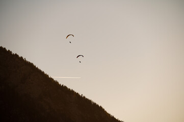 sunset in the mountains with paragliders two flying into the sunset