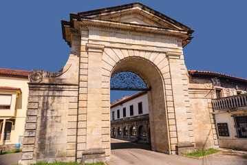 A historical building in the form of a triumphal arch in an urban environment. A modern city road passes under the ancient arch.