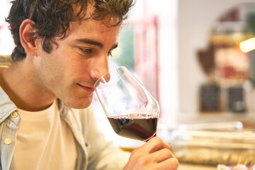 Young man enjoys wine tasting at bar counter.