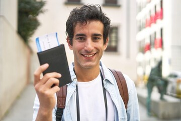 Excited young man proudly displays his airplane tickets while enjoying a vacation in a new and...