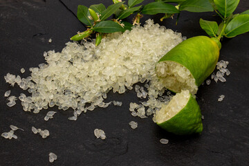 Delicious white citrus caviar on the black slate slab decorated with a green plants sprig and сut finger-shaped ripe fruit, close-up.  Microcitrus australasica, Australian finger lime, Faustrimedin