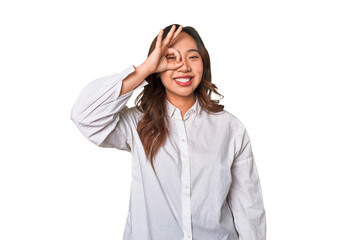 A young chinese woman excited keeping ok gesture on eye.