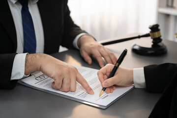 Lawyer signing contract, professional lawyer in law firm library drafting legal document or...