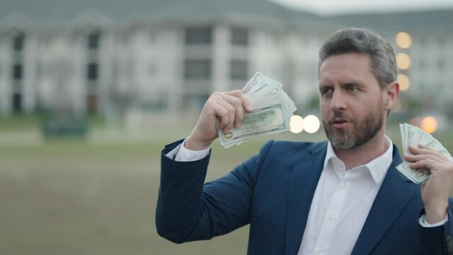 Business man dancing outdoor with 100 dollar bill. Business man hold money outdoor. Rich man in suit with money dollar bills. Successful businessman with dollar banknotes. Rich millionaire in suit.