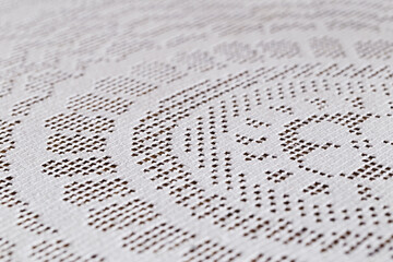 Close up of a white hand crocheted doily with geometric and circular shapes on a table. Selective...