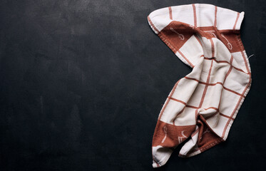 Folded linen linen kitchen towel on a black background, top view