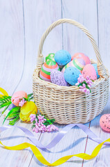 Easter, wicker basket with Easter eggs on a light wooden background. High quality photo